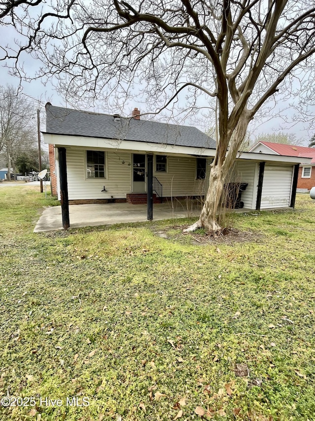 back of house featuring a lawn, a chimney, a patio area, and a shingled roof