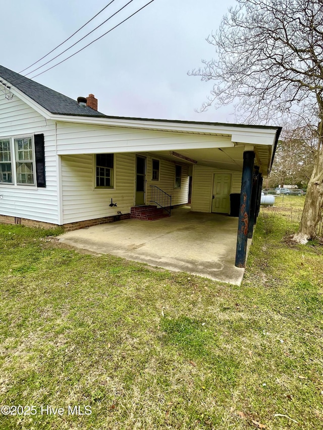 rear view of property featuring a chimney, a carport, and a yard