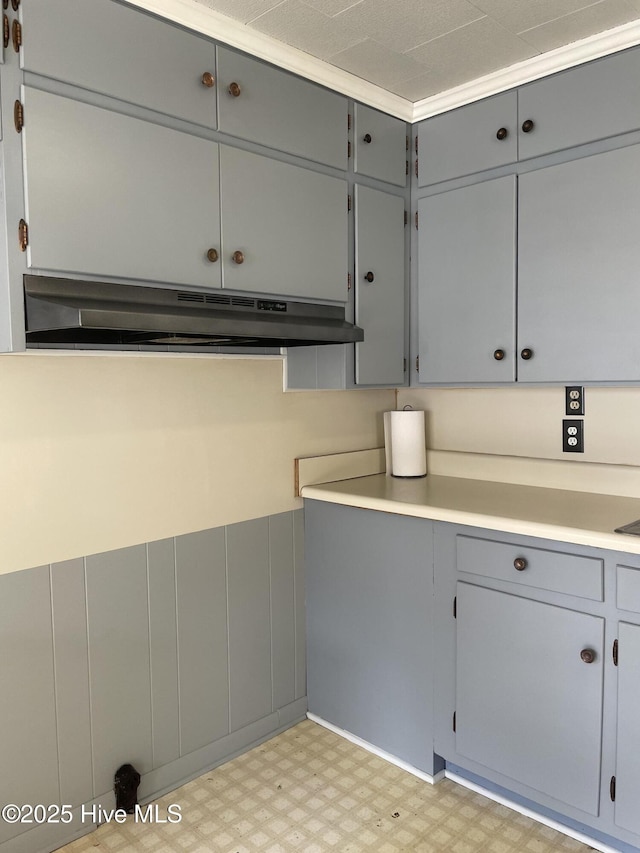kitchen with light floors, gray cabinetry, light countertops, and under cabinet range hood