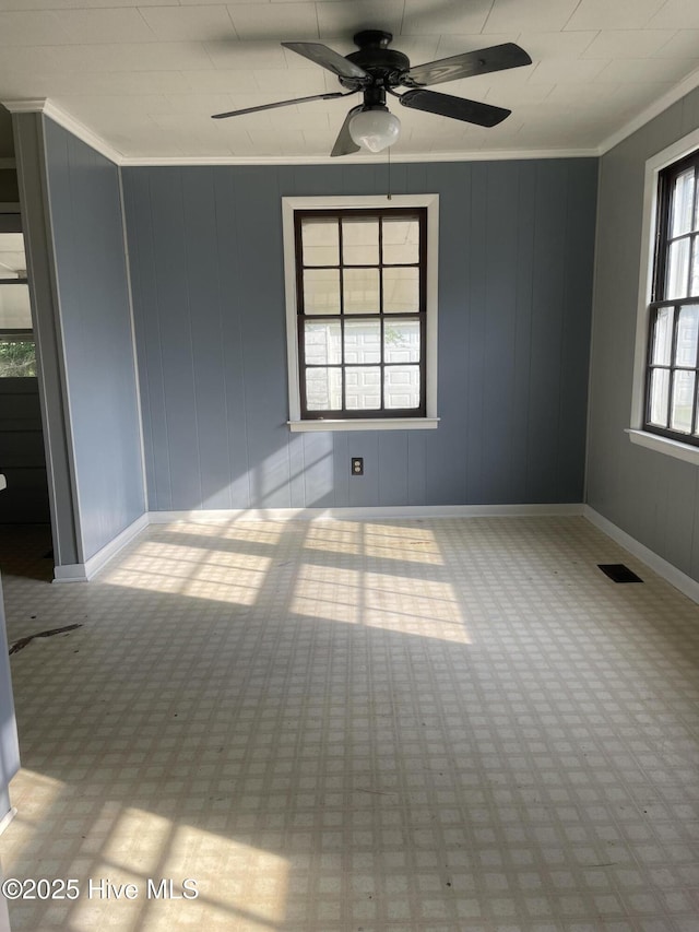 empty room with baseboards, visible vents, ornamental molding, and ceiling fan