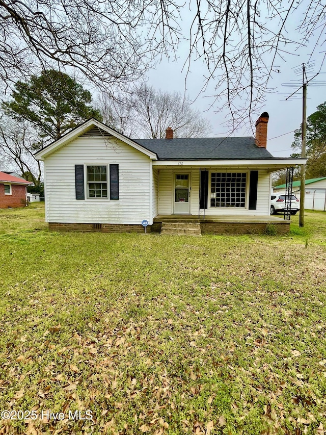 ranch-style home with a front yard, a chimney, a porch, and a shingled roof