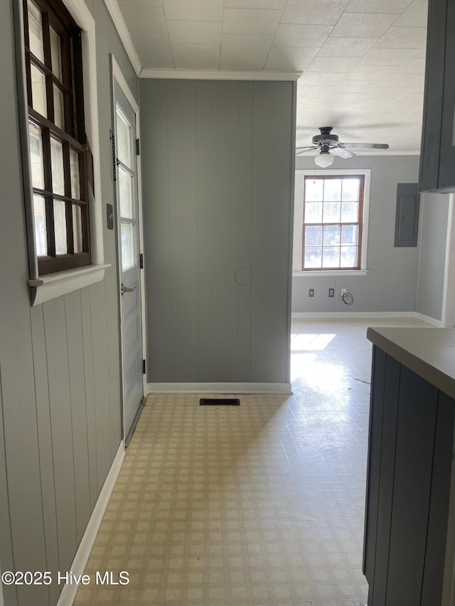 corridor with baseboards, light floors, crown molding, and a decorative wall