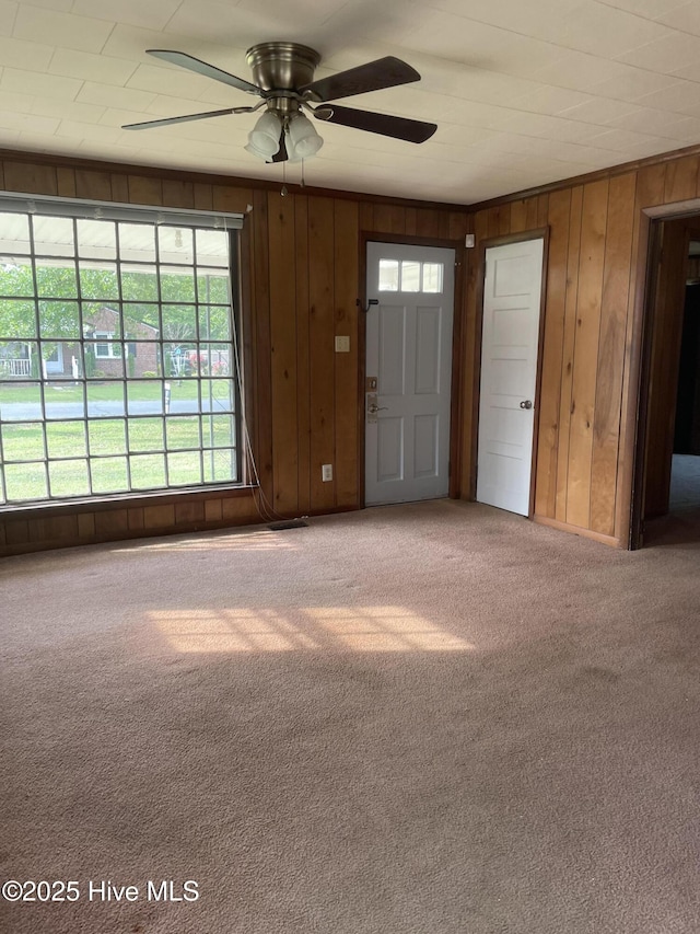 interior space featuring wood walls, a ceiling fan, and carpet floors
