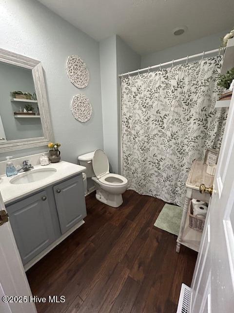 bathroom with vanity, a shower with shower curtain, wood finished floors, visible vents, and toilet