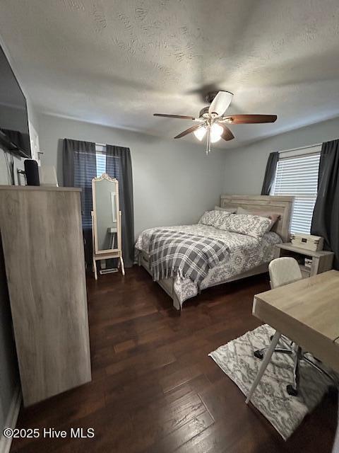 bedroom featuring ceiling fan, wood finished floors, and a textured ceiling