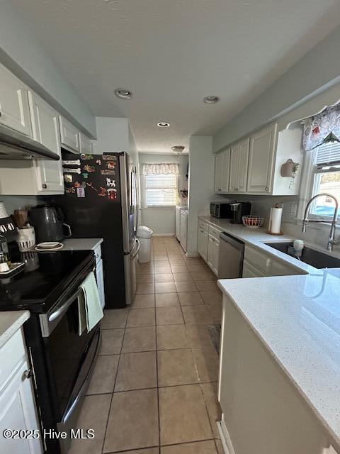 kitchen featuring electric range, light tile patterned flooring, a sink, light countertops, and dishwasher