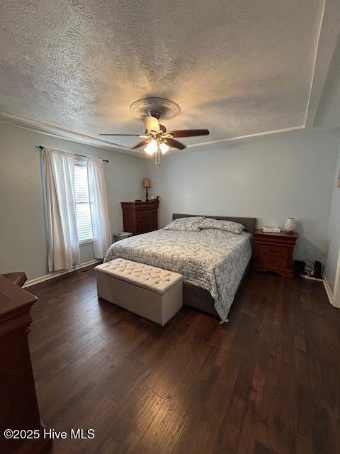 bedroom featuring a ceiling fan, dark wood-style floors, baseboards, and a textured ceiling