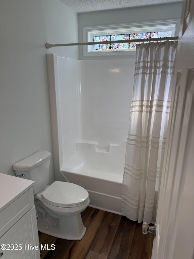 bathroom with shower / bath combo with shower curtain, toilet, a textured ceiling, wood finished floors, and vanity