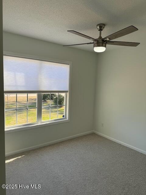 empty room featuring a ceiling fan, baseboards, carpet floors, and a textured ceiling