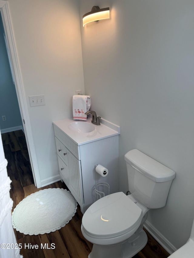 bathroom with vanity, toilet, wood finished floors, and baseboards