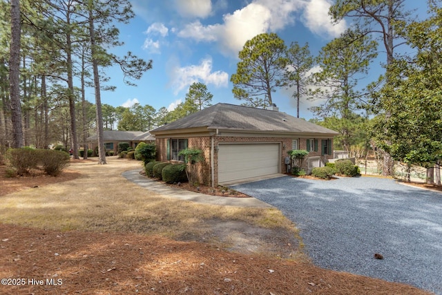 ranch-style house featuring a garage, brick siding, and gravel driveway