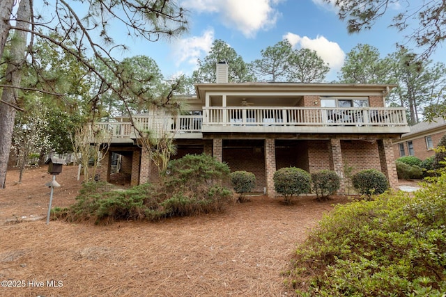 back of property with brick siding, a chimney, and a deck