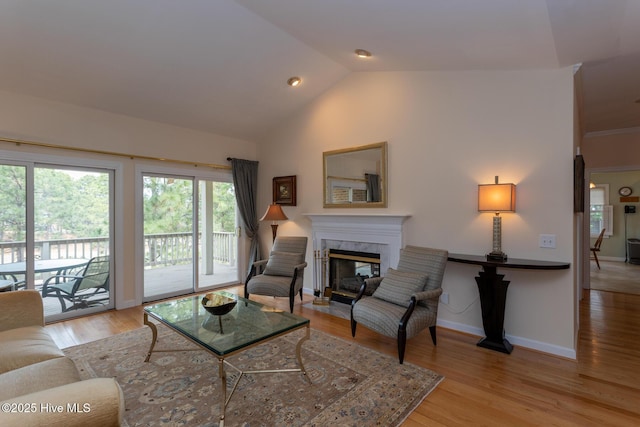 living room with vaulted ceiling, light wood-style flooring, baseboards, and a premium fireplace