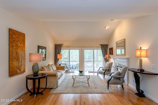 living area featuring baseboards, lofted ceiling, and wood finished floors