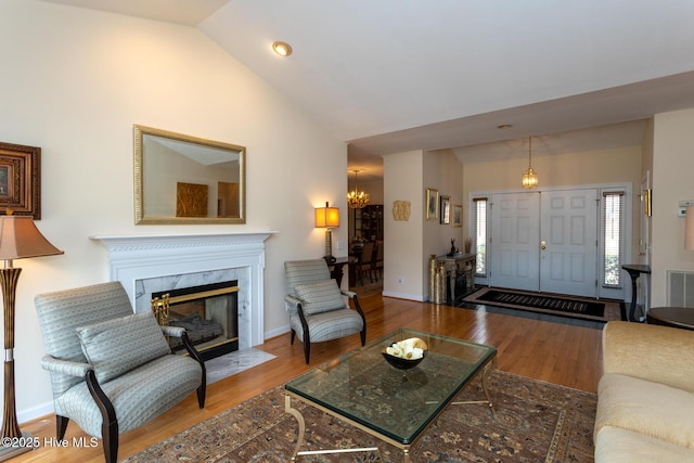 living room with a premium fireplace, baseboards, wood finished floors, and vaulted ceiling