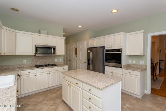 kitchen featuring recessed lighting, appliances with stainless steel finishes, white cabinetry, tasteful backsplash, and a center island