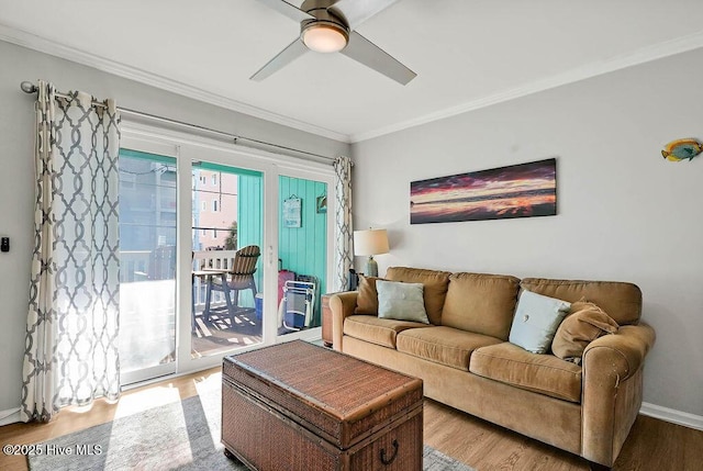 living area featuring baseboards, wood finished floors, a ceiling fan, and ornamental molding