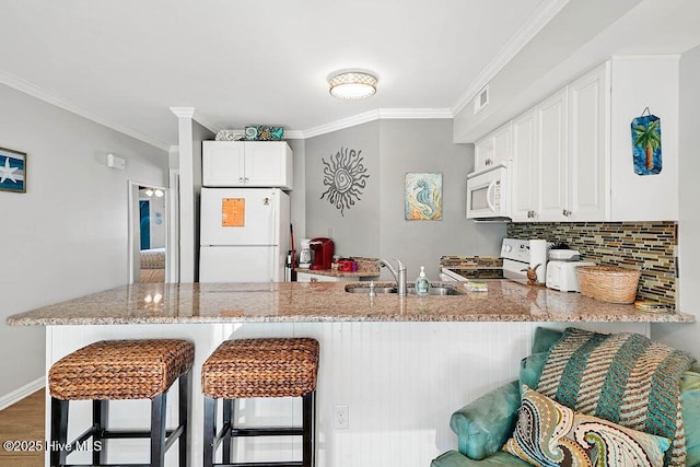 kitchen with white appliances, backsplash, a peninsula, and ornamental molding