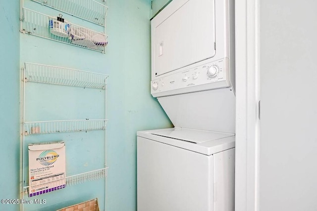 clothes washing area featuring stacked washer and clothes dryer and laundry area