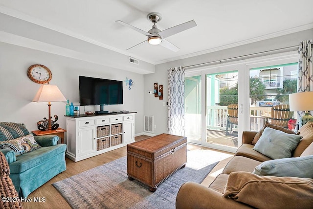 living area with light wood-style flooring, ornamental molding, visible vents, and ceiling fan