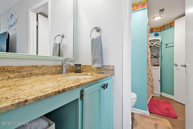 full bath featuring visible vents, toilet, wood finished floors, baseboards, and vanity