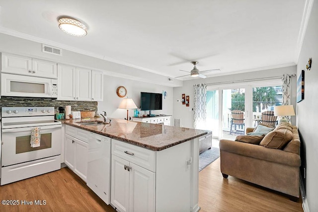 kitchen with white appliances, visible vents, a peninsula, a sink, and open floor plan