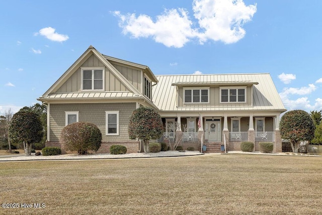 view of front facade featuring board and batten siding, a front lawn, covered porch, metal roof, and a standing seam roof