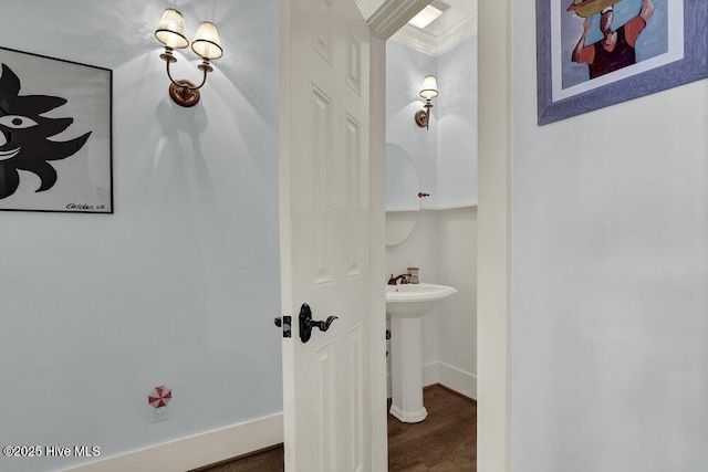 bathroom with wood finished floors, crown molding, baseboards, and a sink