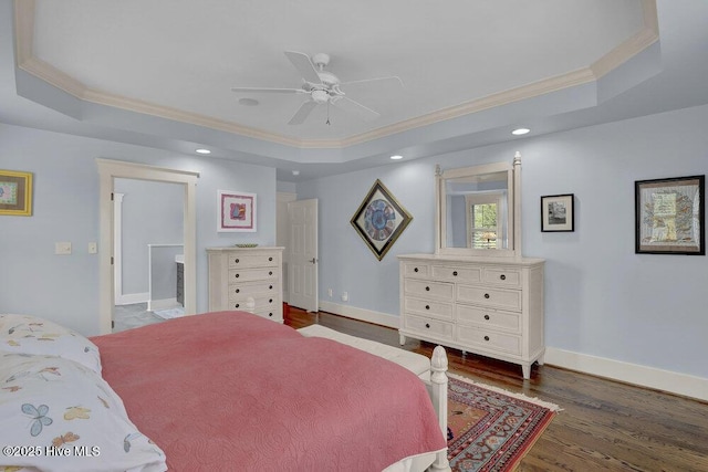 bedroom featuring baseboards, a raised ceiling, wood finished floors, and ornamental molding