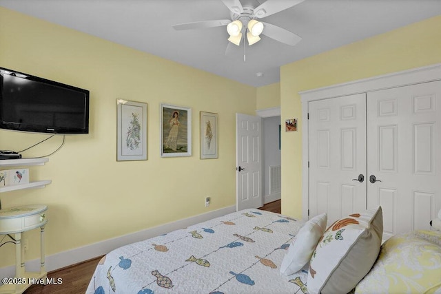 bedroom with wood finished floors, visible vents, baseboards, ceiling fan, and a closet