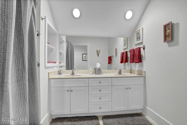 full bathroom with a sink, baseboards, a shower with shower curtain, and double vanity