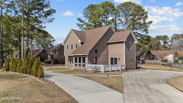 view of front of property featuring driveway, a porch, a front lawn, and a shingled roof