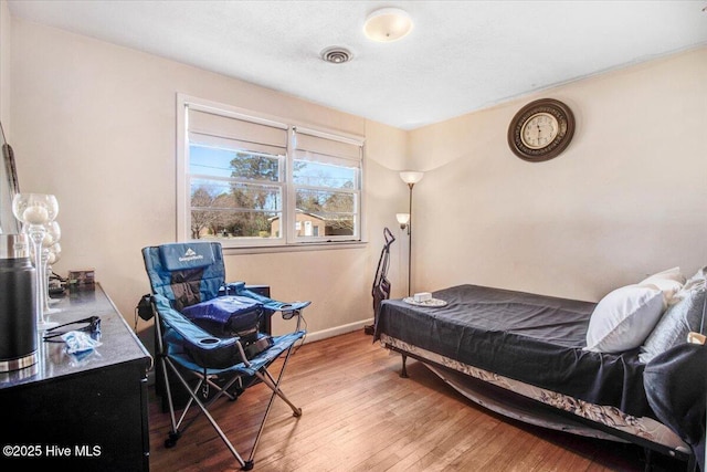 bedroom with visible vents, baseboards, and wood finished floors