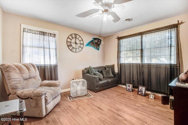 living area with ceiling fan, visible vents, baseboards, and wood finished floors