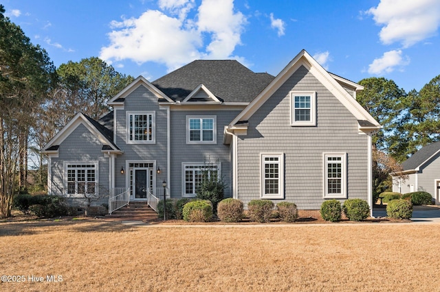 view of front of house with a front yard and a shingled roof