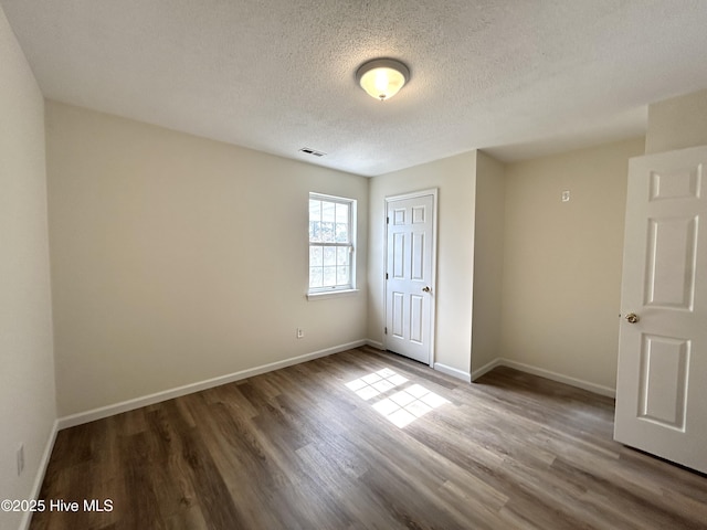 unfurnished bedroom with visible vents, baseboards, a textured ceiling, and wood finished floors