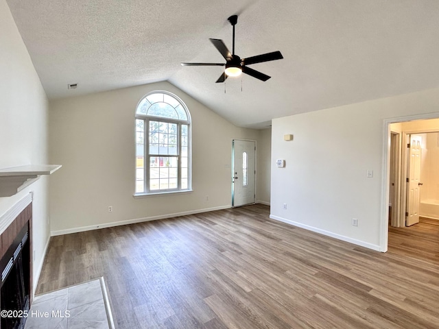 unfurnished living room with a fireplace with flush hearth, lofted ceiling, wood finished floors, and a ceiling fan