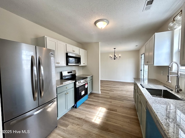 kitchen with visible vents, a notable chandelier, light wood-style flooring, a sink, and stainless steel appliances