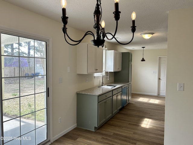 kitchen featuring a sink, baseboards, dark wood finished floors, a textured ceiling, and stainless steel dishwasher