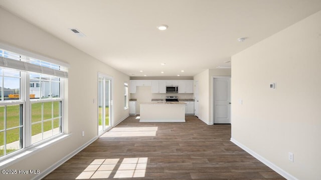 kitchen with dark wood finished floors, white cabinetry, stainless steel appliances, and baseboards