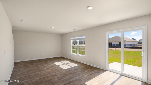 spare room with baseboards, plenty of natural light, and wood finished floors