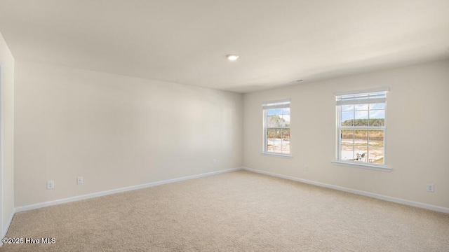 unfurnished room featuring light carpet and baseboards