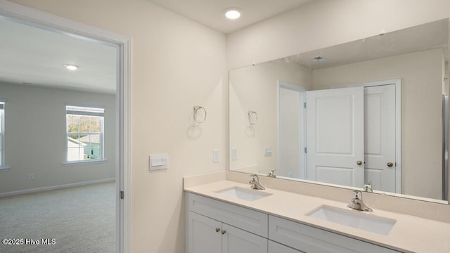 full bathroom featuring double vanity, baseboards, and a sink