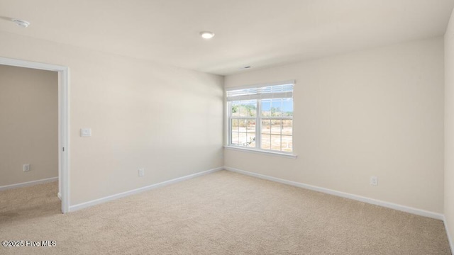 unfurnished room with light colored carpet and baseboards