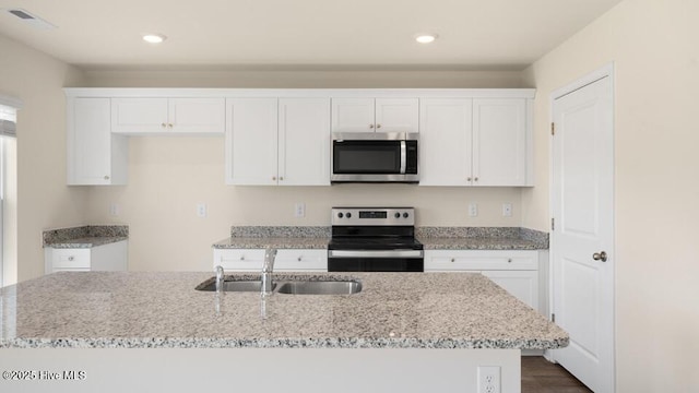 kitchen with recessed lighting, appliances with stainless steel finishes, white cabinetry, and a sink