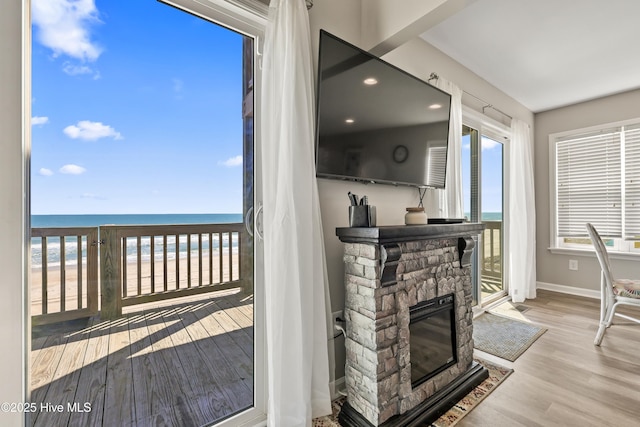 interior space featuring a stone fireplace, wood finished floors, and baseboards