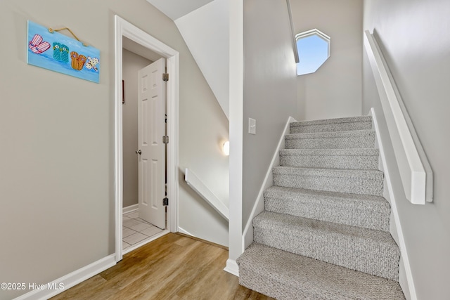 stairs with wood finished floors and baseboards