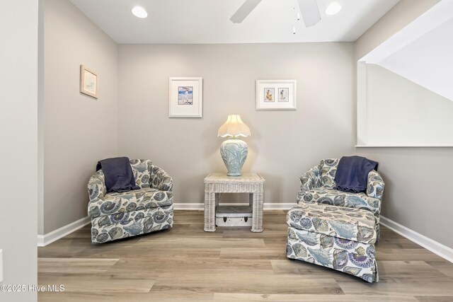 living area with a ceiling fan, baseboards, and wood finished floors