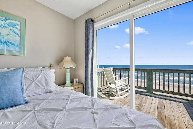 bedroom with multiple windows, access to outside, wood finished floors, and a water view