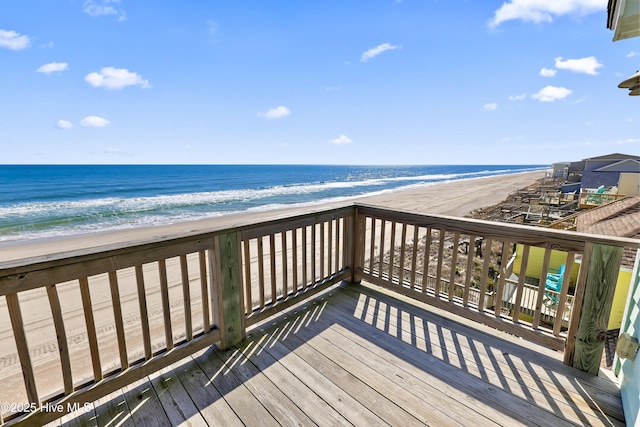 wooden terrace featuring a water view and a view of the beach